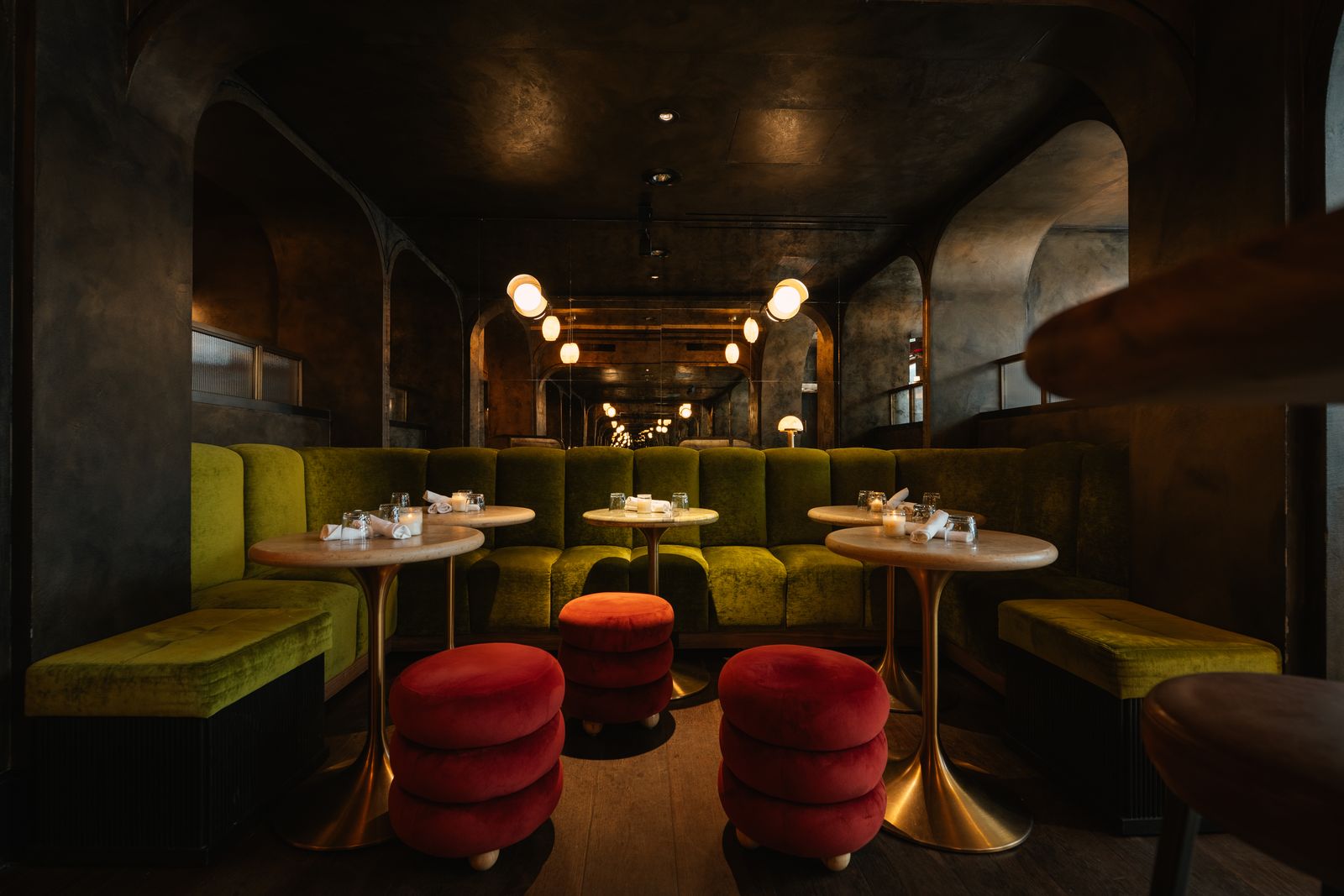 Empty marble tables between green velvet booths