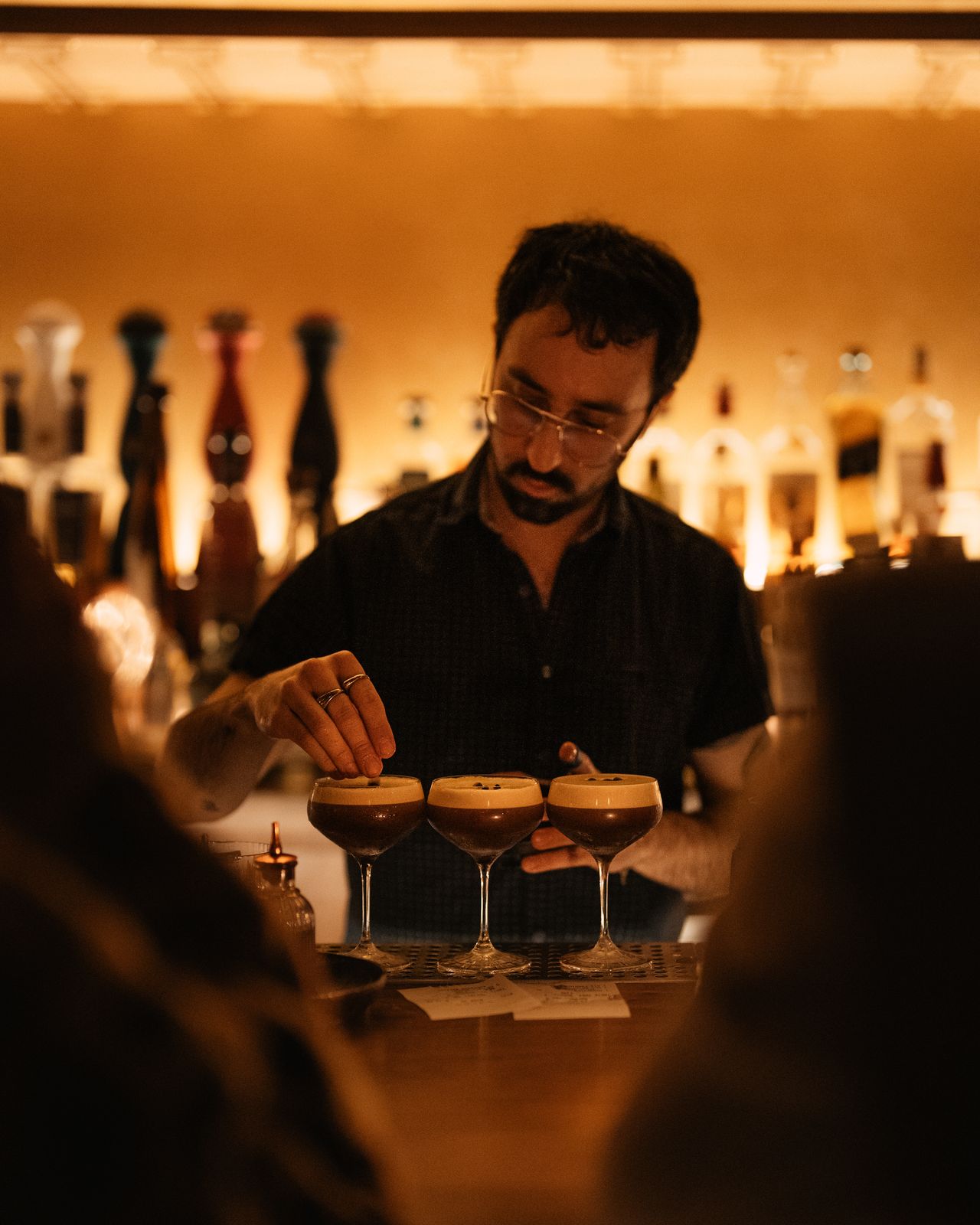 Bartender finishing three espresso martinis with coffee beans